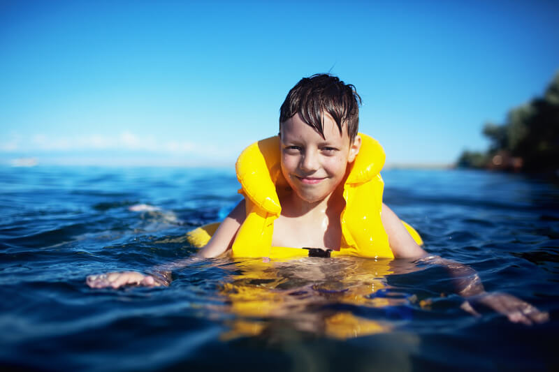 Smiling boy in the life-vest in the water