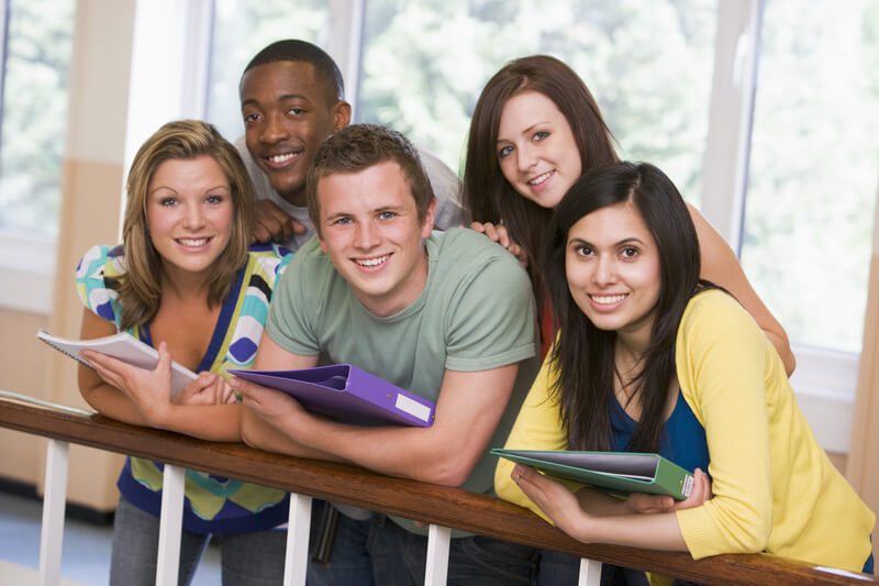 Group of college students leaning on banister.